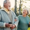 Senior couple, park and morning walk with conversation, love and bonding together with health. Wellness, marriage and retirement with outdoor, communication and coffee on urban garden path on date