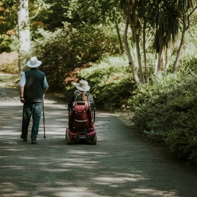 Happy senior couple enjoying the outdoors, a key benefit of buying a mobility scooter.
